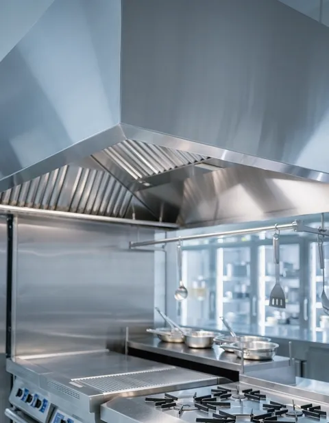 Technician cleaning a commercial kitchen exhaust hood