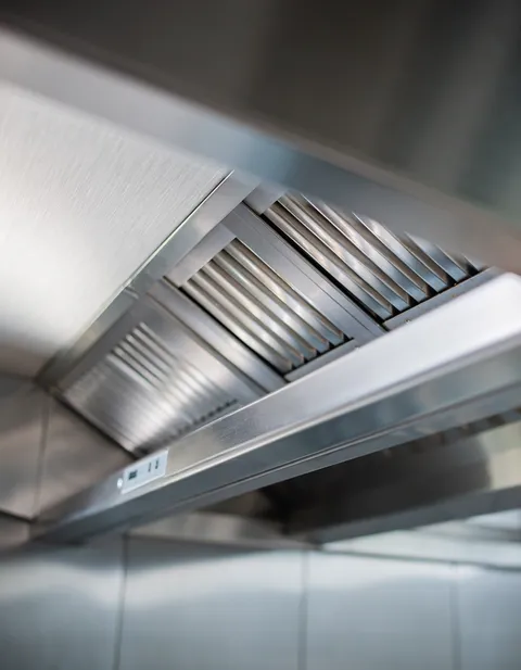 Technician cleaning a commercial kitchen exhaust hood